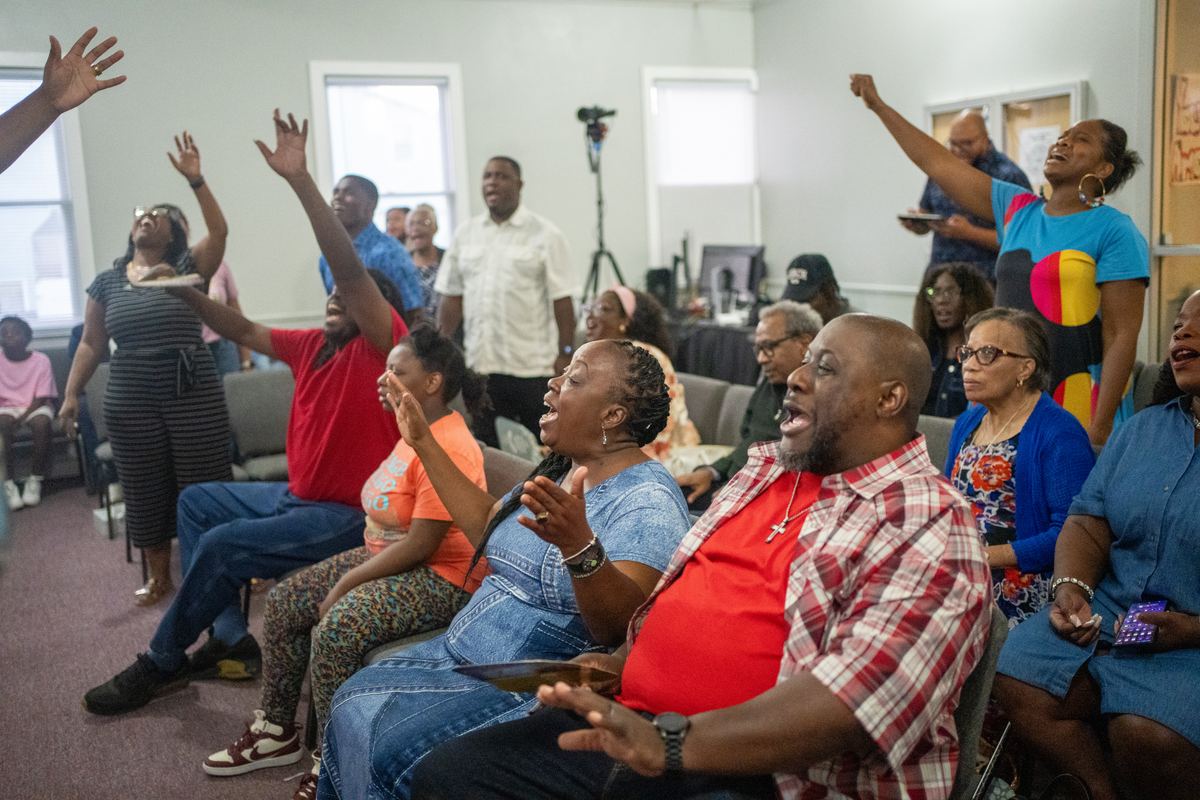Members of Christ Church Triumphant standing with hands raised, singing and worshiping together