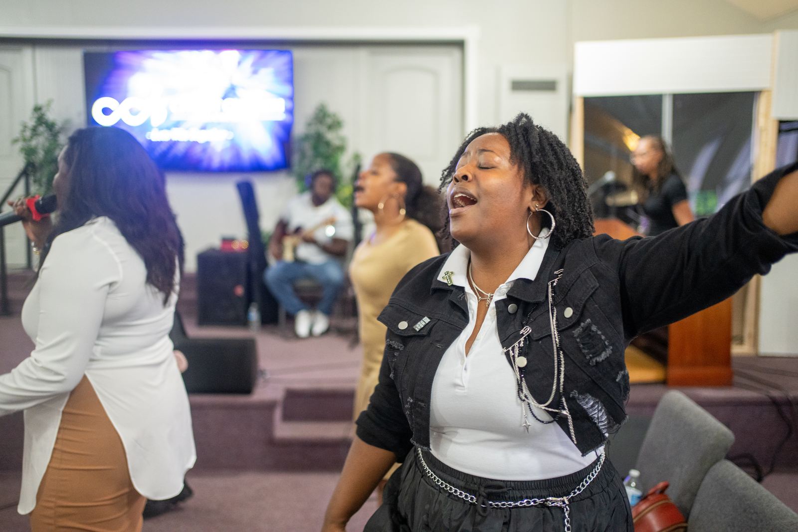 A worship leader singing with eyes closed and arms outstretched