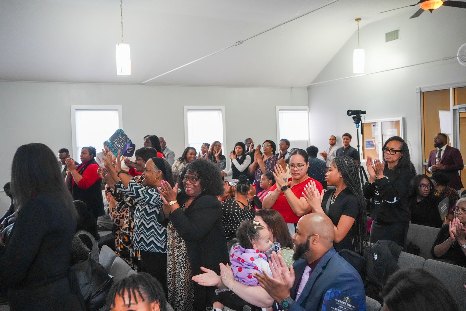 The congregation on its feet, clapping and celebrating during worship