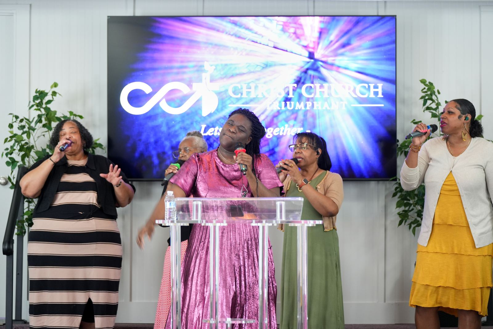 The worship team singing together in front of the Christ Church Triumphant screen
