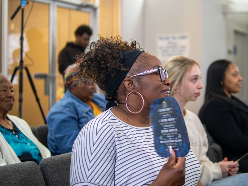A smiling church member holding a fan, joining in during worship